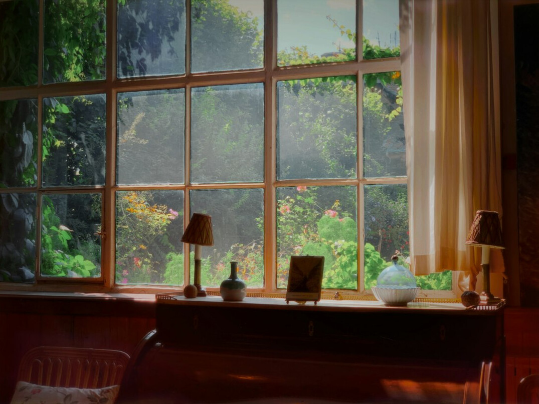 Wooden desk with notebook and fountain pen by a garden window